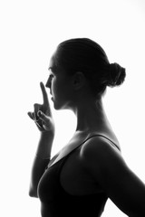 Fototapeta na wymiar Profile of young atletic girl with forefinger close to her face (silence sign)