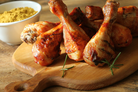 Grilled chicken legs on cutting board. Rustic background