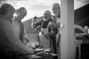 group of aged people doing barbecue on the rooftop enjoying the retired time