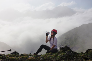 Girl hiker drinking water on the mountain.