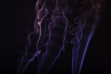 Red and blue smoke from incense sticks, forming strange shapes, on a black background.