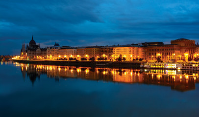 Pest downtown riverfront at night, reflecting in still Danube water. Budapest, Hungary