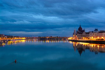 Still Danube river at dawn, reflected highlighted shores, Parliament domes. Budapest, Hungary