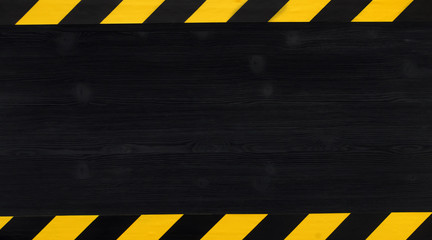 Under construction concept background. Warning tape frame on black wooden surface background with copy space.