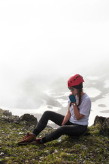 Girl in a hike sits on top of a mountain.