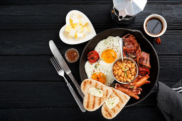 Traditional full English breakfast with fried eggs, sausages, beans, grilled tomatoes and bacon.