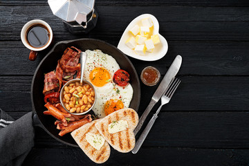 Traditional full English breakfast with fried eggs, sausages, beans, grilled tomatoes and bacon.