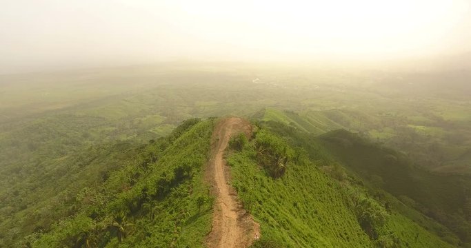 Aerial drone bird's eye view video on a mountain covered with green grass. On top of the mountain there is a farm. tropical paradise pacific atoll islands. Top view. Shot in 4k