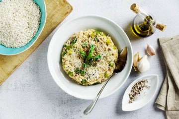 Italian risotto with spring fresh asparagus and parmesan cheese in a plate and ingredients on a stone white table