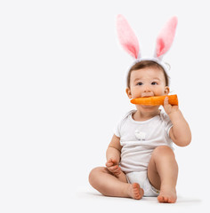 Portrait of a child in a rabbit costume with a carrot in his hands. Photo indoors