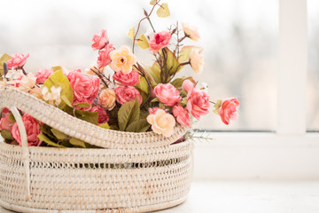 Obraz na płótnie Canvas colorful roses in a basket on window-sill