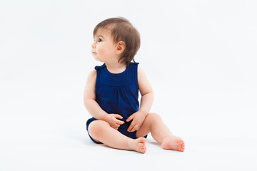 Cute funny small smiling girl sitting in studio posing on white background