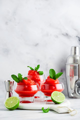 Berry Slushie with lime, Summer refreshing drink in serving glasses. bartender tools in the background