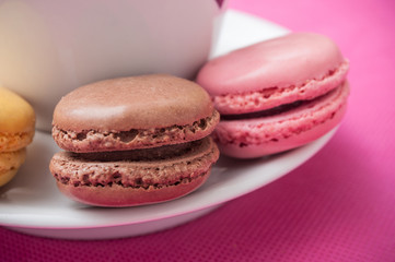 Obraz na płótnie Canvas assortment of french macarons pastry and cupof coffeee on pink background