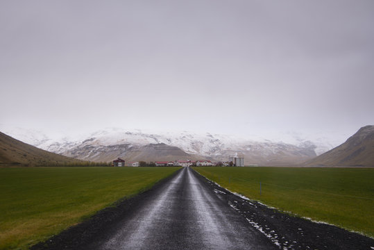 Country Road Towards Town Against Mountains And Sky During Winter