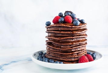 a stack of chocolate gluten free pancake with fresh berries. morning healthy breakfast