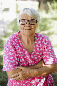 Portrait of senior woman with arms crossed wearing eyeglasses at backyard