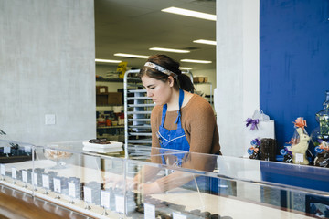 Female owner arranging chocolates in display cabinet at store
