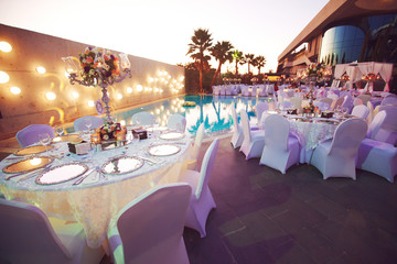 Wedding celebration dinner at sea side hotel near swimming pool surrounded with palms