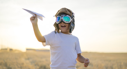 Kid, Little boy wearing helmet and dreams of becoming an aviator while playing a paper plane at...
