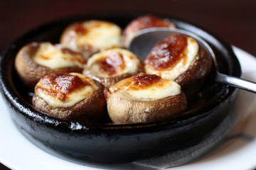 mushrooms  baked with cheese on a black frying pan