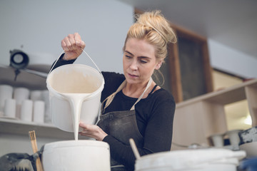 Woman pouring paint in container at workshop