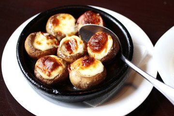 mushrooms  baked with cheese on a black frying pan