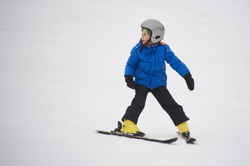 Child boy skiing in winter mountains. Active kid with safety helmet and goggles. Ski race for young children. Winter sport for family. Kids ski lesson in school. Young skier racing in snow