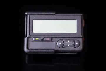 Old black pager isolated on black background