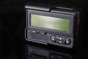 Old black pager or beeper isolated on black background. Vintage gadget for communication device