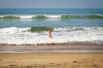 Young woman dancing and playing with ocean waves.