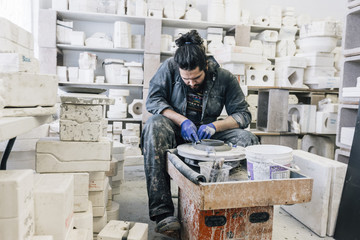 Craftsman using pottery wheel while working in workshop