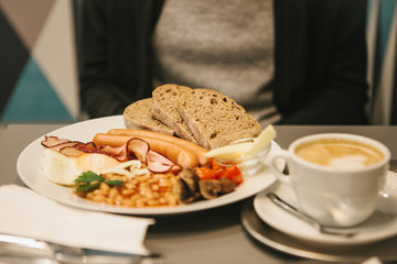 Traditional English breakfast. A cup of coffee with cappuccino is next to it. National food. A famous dish all over the world.
