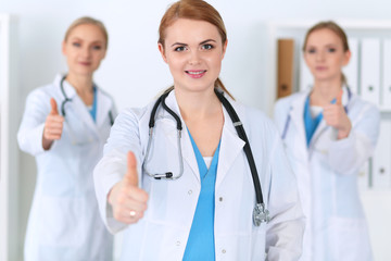 Fototapeta premium Groupe of medicine doctors show OK sign with thumb up. Success and high level service in health care, best treatment and customer loyalty and physical concept. Copy space for advertisement