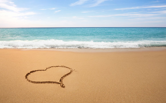 Heart shape drawn on the sand at the empty tropical beach with copy space