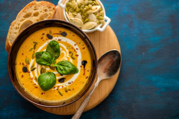 Delicious homemade pumpkin soup with basil leaves. Top view. Copyspace.