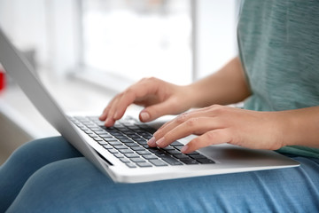 Young woman using laptop indoors, closeup
