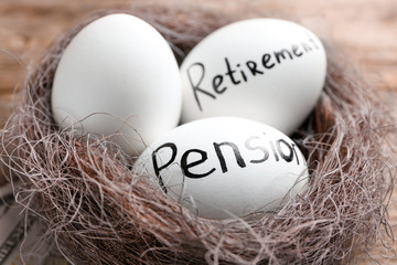 Eggs with words PENSION and RETIREMENT in nest, closeup