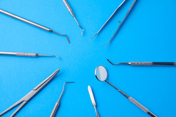 Dental metal instruments, mirror, stylus on a blue background in the form of the sun