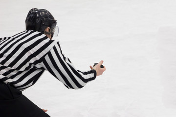 Hockey referee holding a puck in face off position. Back view. White background, isolated.