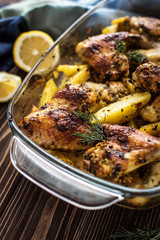 Baked chicken wings with potatoes on a wooden background