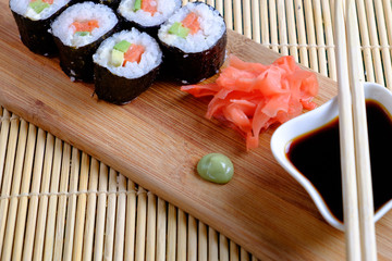Ready rolls on a wooden stand, ginger, soy sauce, wasabi, wooden sticks