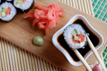 Girl holding chopsticks ready to roll, soy sauce, top view