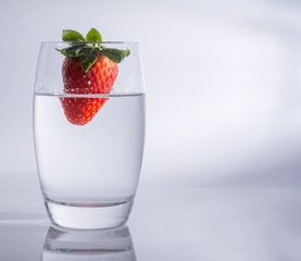 Erdbeere fällt in das Glas mit Wasser