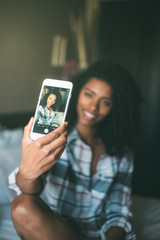 pretty black woman making a selfie on bed smiling