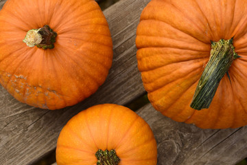 Three bright orange pumpkins on wood