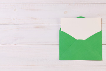 Top View of a invitation or Letter with a Green Envelope. Message or Ticket on Wooden White Desk or Table. Writing a note. Pen, Pencil, a Blank Notebook. Picture. Copy space for text or Image.
