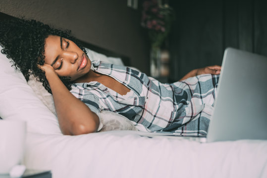 beautiful black woman on bed with laptop sleeping