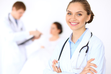 Cheerful smiling female doctor on the background with physician and his patient in the bed