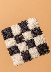 Black and white rice in a checkerboard pattern on orange background top view